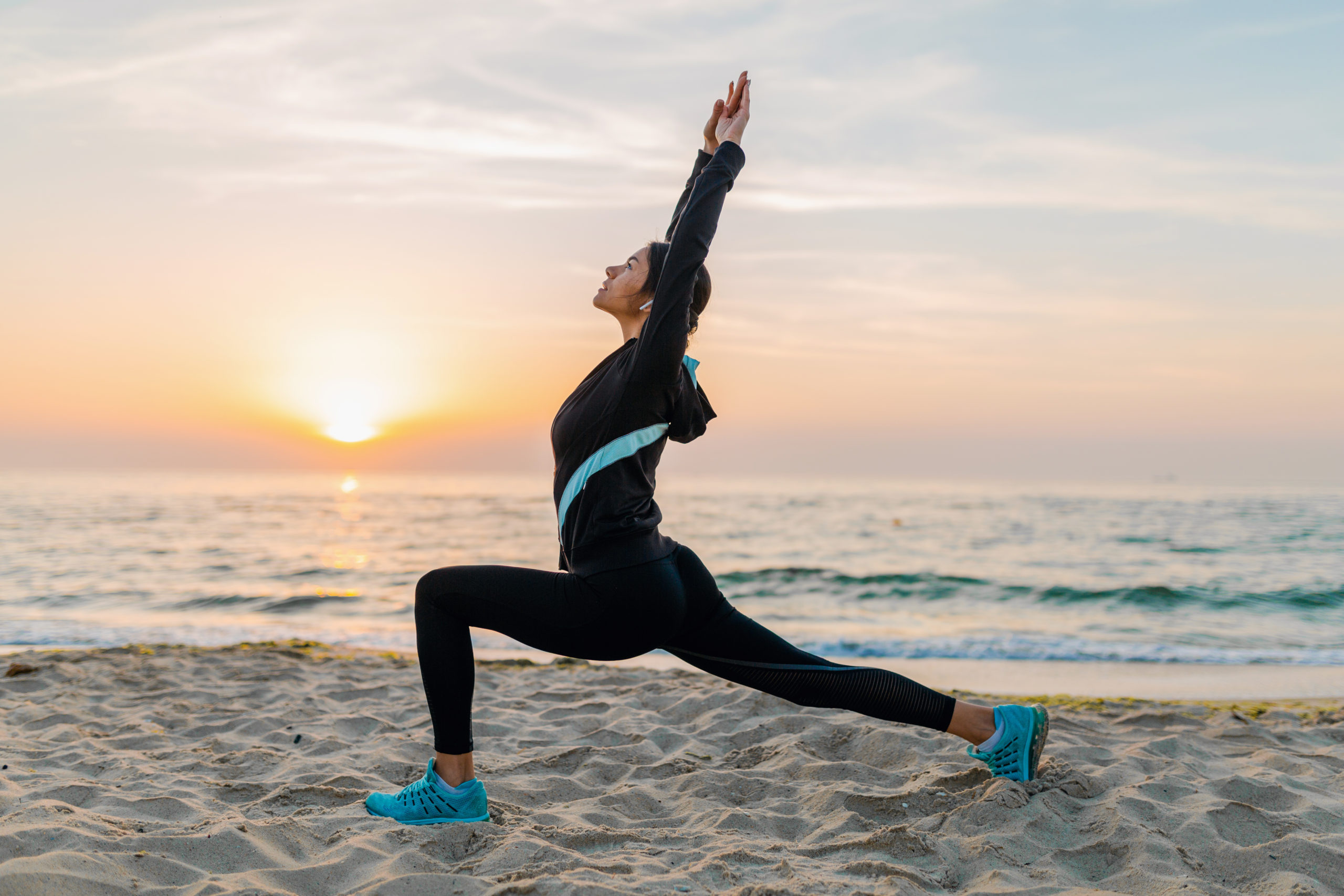 Free Photo  Young woman doing sport exercises on sunrise beach in morning